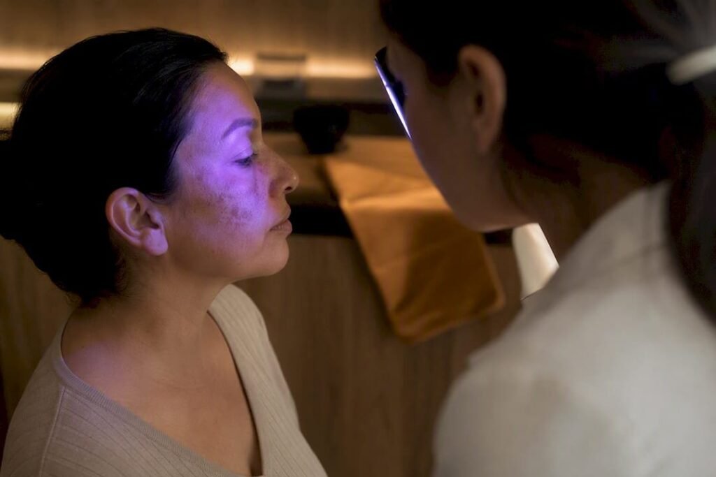 Médecin examinant des taches brunes du visage à la lampe de Wood dans un centre laser